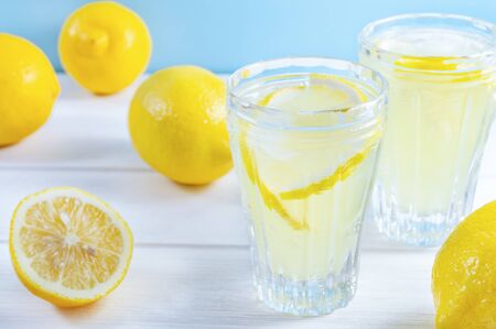 Glasses with summer drink lemonade and lemon fruit on white wooden table.の写真素材