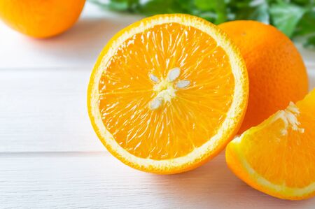 Fresh oranges and green leaves on white wooden table.の写真素材