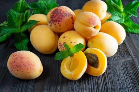 Fresh apricots and mint leaves on dark wooden background.の写真素材