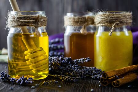 Lavender and herbal honey in glass jars with honey spoon on dark wooden background.の写真素材