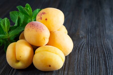Fresh apricots and mint leaves on dark wooden background.の写真素材