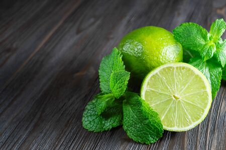 Fresh lymes and mint leaves on a dark wooden background.の写真素材