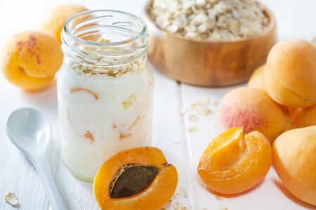 Oatmeal milkshake, smoothie or yogurt with fresh apricot on a white wooden table.の写真素材