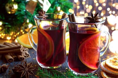 Christmas mulled red wine with spices and oranges on old wooden table. Traditional hot drink at Christmas.の写真素材
