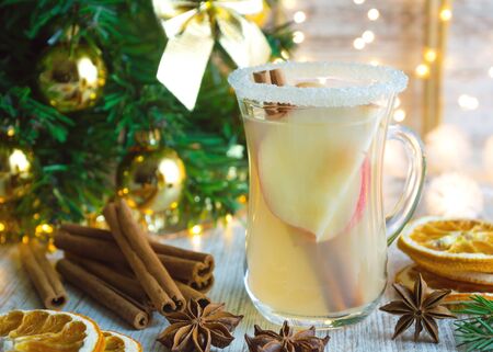 Christmas hot white mulled wine in glass with apples, cinnamon sticks and star anise on wooden background. Traditional hot drink at Christmas.の写真素材