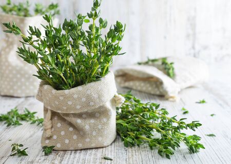 Fresh green thyme in decorative linen bag on an old wooden table.の写真素材