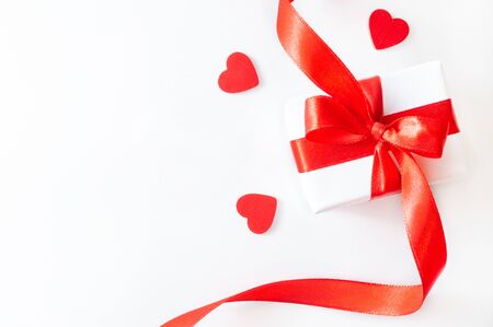 Gift or present box with red ribbon, and decorative hearts on white background. Holiday concept, flat lay, top viewの写真素材