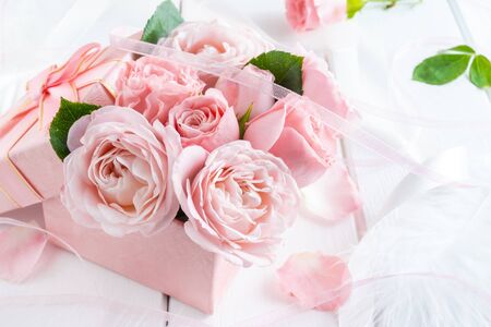 Beautiful pink flowers in gift box with ribbons closeup on white wooden table.の写真素材