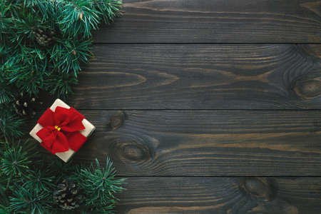 Old wooden background with fir branches and gift box. Christmas card, flat lay, top view, copy space.の写真素材