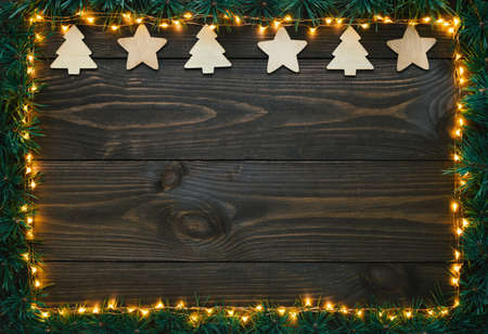 Christmas decoration, christmas lights and fir branches on old wooden background. Flat lay, top view, copy space.の写真素材
