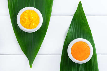 Natural organic cosmetics: orange scrub and sea salt on white wooden background with green leaves. SPA and body care concept. Flat lay, top view.の写真素材
