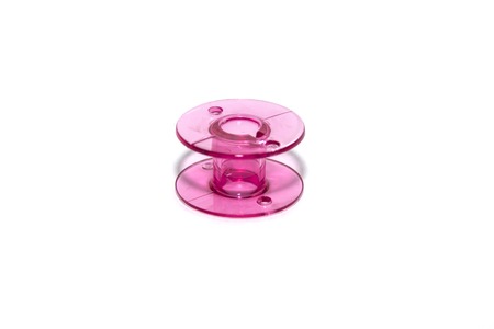 pink plastic bobbin for sewing machine on white backgroundの写真素材