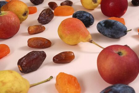 Superfoods on a pink background. Apples pears plums dates dried apricots