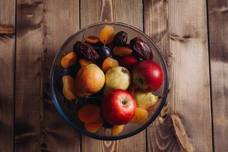 dried apricots and dates plate, plum, apple, pear in a plate, closeup shotの写真素材