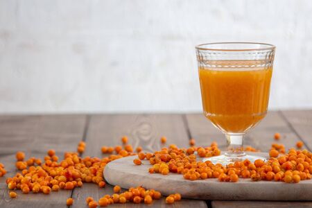 sea buckthorn of the morse in a beautiful glass on a wooden background of berries scatteredの写真素材