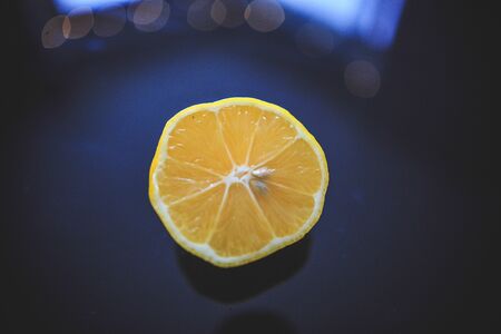 Meyer lemon of orange color originating in China taken from 45 degree angle on the black reflective background.の写真素材