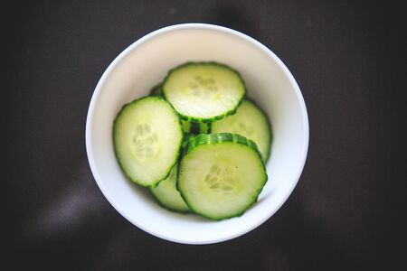 Close-up of cucumber slices in the white bowl with exotic green color and light gray background.の写真素材