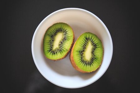 Close-up of kiwi halves in the bowl with exotic green color and black background.の写真素材