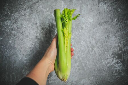 Fresh green celery holding in hand on the white and gray background.の写真素材