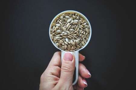 Natural sunflower seeds without shell in the white measuring cup taken from the top on the back background.の写真素材