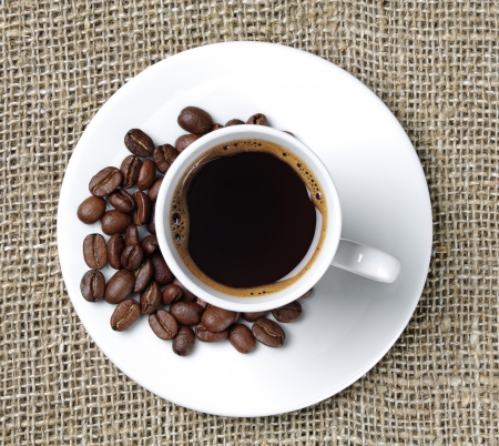 Cup of coffee on a background fabric and coffee beansの写真素材