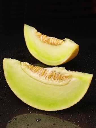 Two melons slices on a background with drops closeupの写真素材