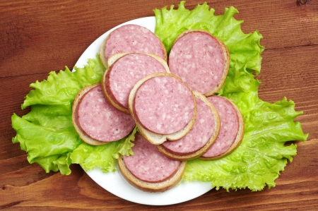 Sandwiches with sausage and lettuce on a plate on wooden tableの写真素材