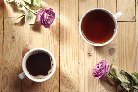 Cup of coffee, tea and two dried roses on a wooden tableの写真素材
