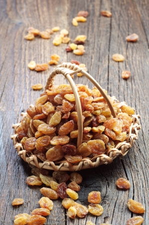 Raisin in a wicker basket and near on old wooden tableの写真素材