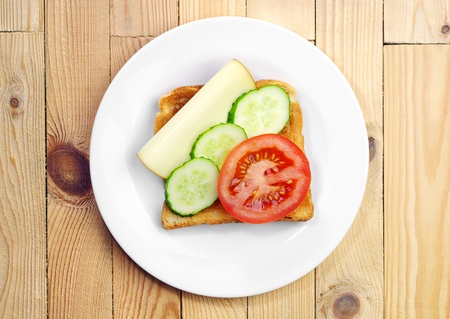 Toast with cheese, tomato and cucumber on a plate on the table  Top viewの写真素材