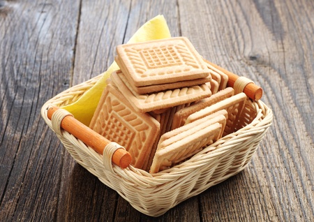Cookies in the shape of a square in wicker basket on a wooden tableの写真素材