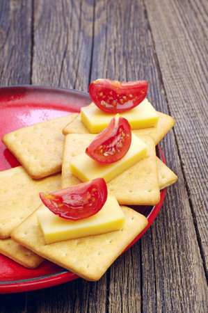 Crackers with cheese and tomato on old wooden tableの写真素材