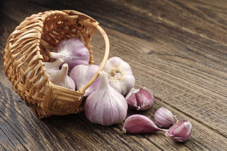 Garlic in a wicker basket and near on wooden tableの写真素材