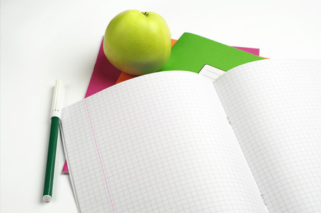 Opened school notebook, felt-tip pens and green apple
