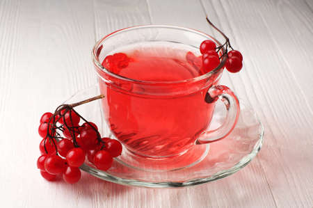 Cup of tea with viburnum berries on white wooden tableの写真素材