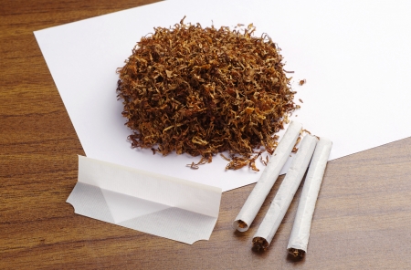 Tobacco and hand rolled cigarettes on tableの写真素材