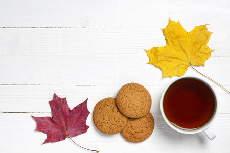Cup of tea, biscuits and maple leaves on a white wooden tableの写真素材