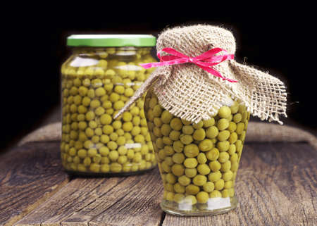 Canned green peas in glass jar on wooden tableの写真素材