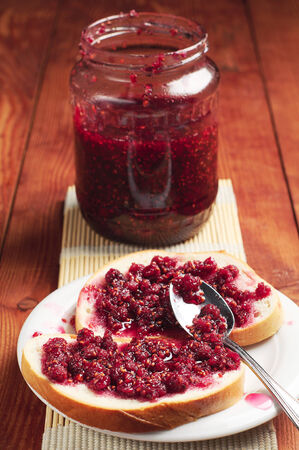White bread and glass jar with raspberry jam