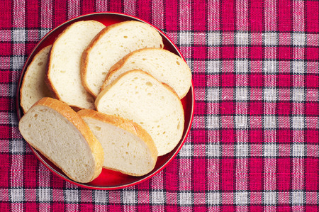 Top view of slices bread in plate on a red tablecloth