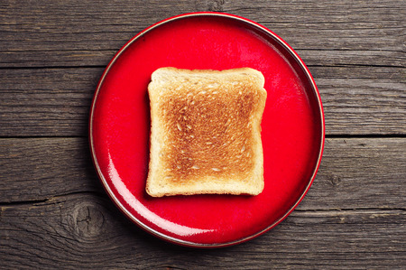 Toast bread in a brown plate on vintage wooden background. Top view