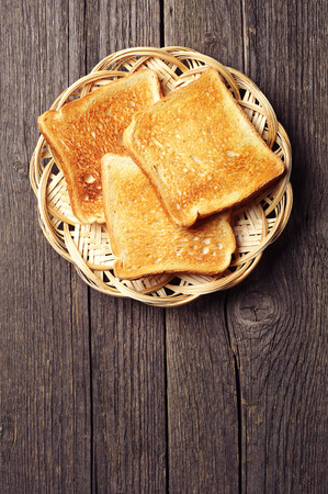 Toast bread in a wicker plate on vintage wooden background. With place for text.の写真素材