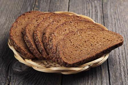Bread in a wicker plate on vintage wooden table closeup