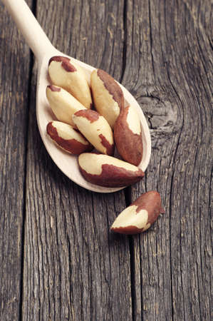 Brazil nuts in spoon on vintage wooden backgroundの写真素材