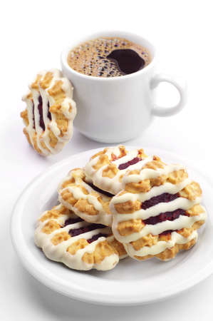 Sweet cookies with jam and icing and cup of coffee on white background