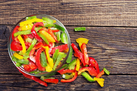 Top view on frozen paprika slices in glass bowl on wooden backgroundの写真素材
