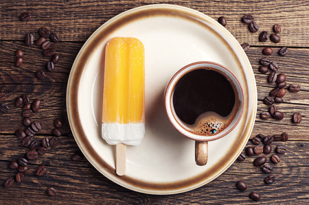 Top view of a cup of coffee and orange ice cream on wooden tableの写真素材