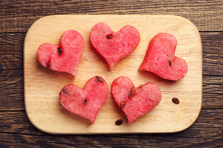 Slices of watermelon in the shape of hearts on a cutting board. Top viewの写真素材