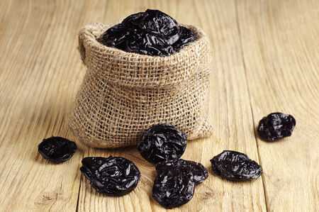 Dried plum in sack on wooden tableの写真素材