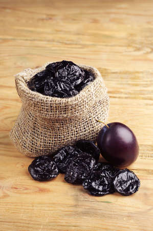 Prunes in sack on vintage wooden backgroundの写真素材